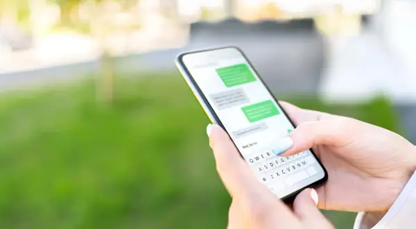 Dłoń trzyma smartfon z widoczną klawiaturą. Dowiedz się, jak przywrócić ustawienia klawiatury w telefonie, gdy coś pójdzie nie tak.