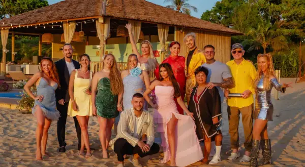 Die Besetzung von "Kampf der Realitystars" posiert am Strand vor einer Hütte.