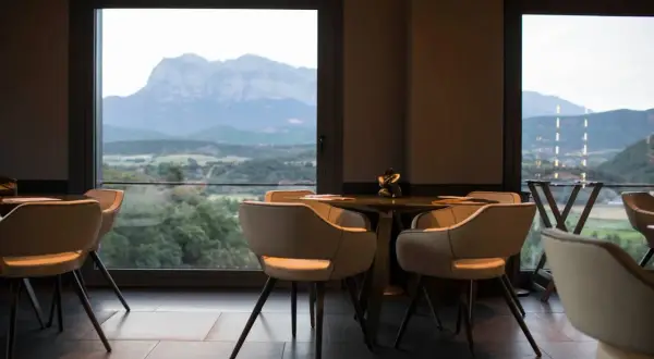 Mesas y sillas en un restaurante con vistas a montañas y valles, como si fueran soles Repsol en Aragón.