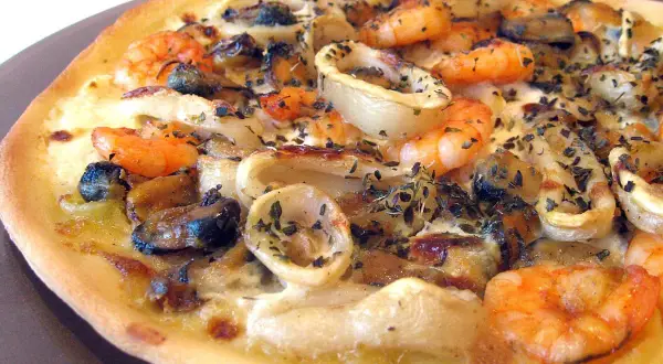 Une délicieuse pizza fruit de mer, garnie de crevettes, moules et calamars, saupoudrée d'herbes.