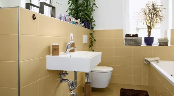 Bagno moderno con piastrelle color sabbia, lavabo sospeso, WC e vasca. Un'idea per dipingere piastrelle bagno con un tocco di calore.