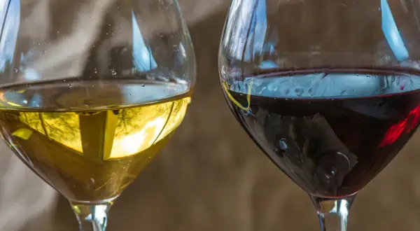 Dwa kieliszki wina, białe i czerwone. Czerwone wino może mieć skutki uboczne, ale oba napoje kuszą smakiem.