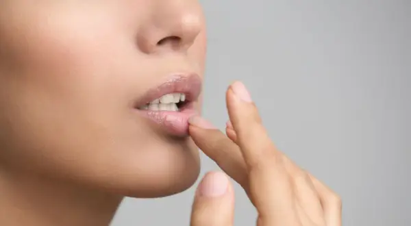 Une femme applique un baume sur ses lèvres. Si vous avez des lèvres gercées, que faire ? Hydratez-les !