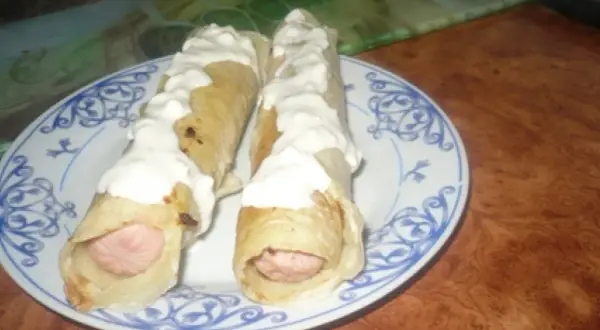 Dwa parówki w cieście naleśnikowym, polane sosem. Pyszna przekąska na szybko.
