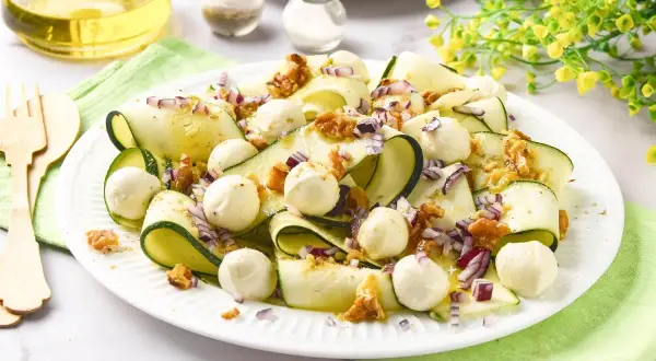 Deliciosa ensalada de calabacín en cintas, con bolitas de mozzarella, nueces y cebolla morada. Un plato fresco y ligero.