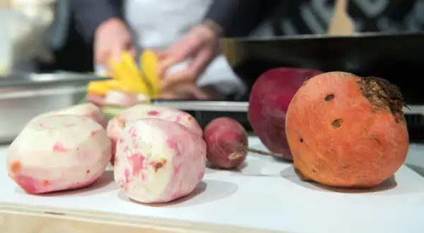 Bunte Bete, frisch geschält und bereit für die Zubereitung. Eine rote und eine orangefarbene Bete liegen daneben.