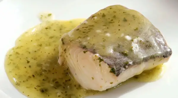Filete de pescado blanco bañado en una sabrosa salsa verde, con hierbas picadas y un toque de ajo.