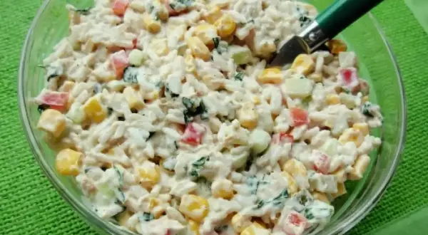Pyszna sałatka z tuńczykiem, ryżem, kukurydzą, papryką i ogórkiem, polana kremowym sosem. Idealna na szybki lunch.