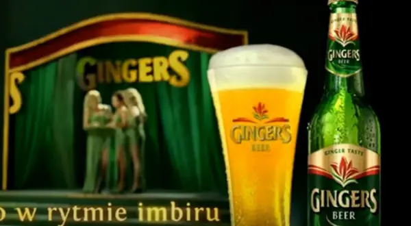 Piwo Gingers: orzeźwiający smak imbiru w szklance i butelce, na scenie z tancerkami.