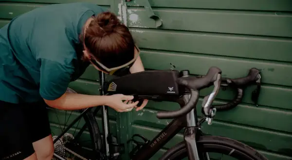 Osoba montuje torbę podsiodłową do roweru. Przygotowania do składania roweru przed wyprawą.