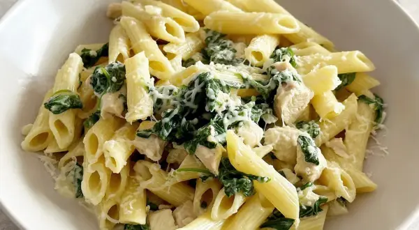 Penne z kurczakiem, szpinakiem i fetą, posypane parmezanem. Pyszne danie, które zachwyci każdego.