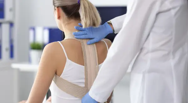 Medico applica un busto correttivo a una giovane donna. La domanda "fino a che età si può mettere il busto" è centrale per il trattamento.