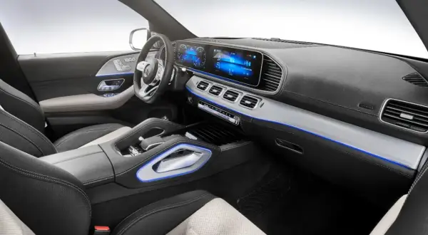 Interior de un Mercedes moderno, con pantallas digitales, asientos de cuero y detalles de iluminación ambiental azul.