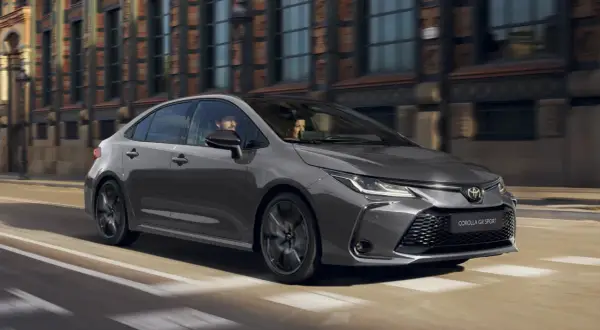 Szara Toyota Corolla GR Sport jedzie ulicą miasta. W środku siedzi para.