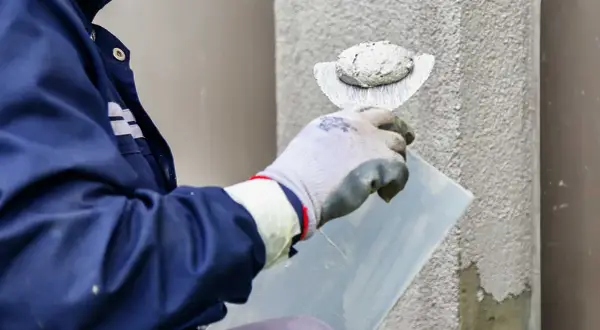 Pracownik nakłada tynk silikonowy na ścianę. Sprawdź atrakcyjną cenę za m2 robocizny.