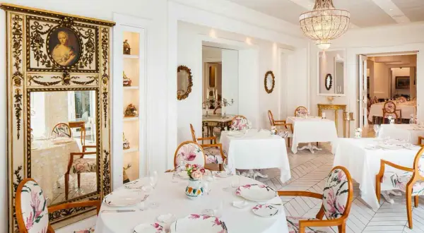 Eleganza e raffinatezza nel ristorante Don Alfonso, dove le stelle Michelin brillano in un ambiente da sogno con arredi floreali e un maestoso lampadario.