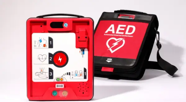 Czerwony defibrylator AED i torba z napisem AED. Urządzenie gotowe do użycia w przypadku nagłego zatrzymania krążenia, gdy występuje asystolia.