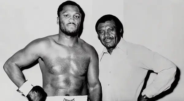 Joe Frazier, known for his impressive joe frazier height, stands with his trainer.