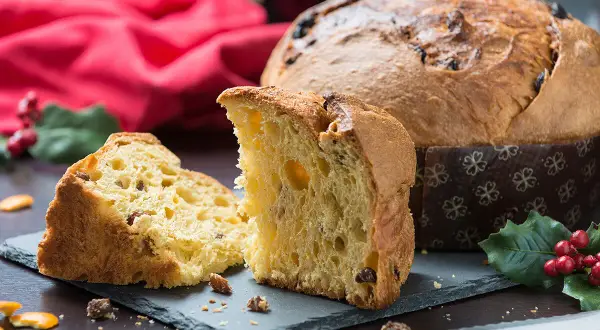 Un delicioso panettone, un dulce navideño italiano, cortado en rebanadas, con pasas y frutas confitadas.