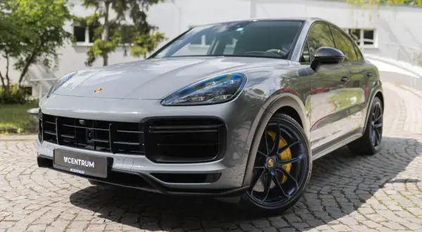 Szary Porsche Cayenne Turbo GT z żółtymi zaciskami hamulcowymi stoi na brukowanej nawierzchni.