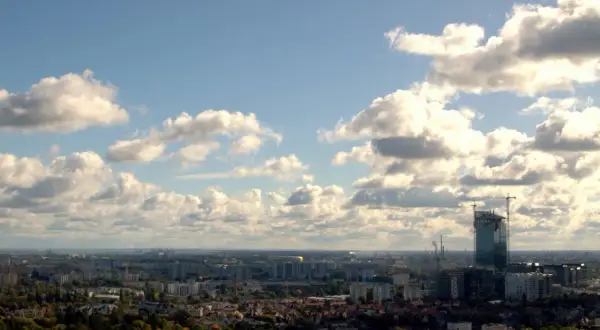 Widok na Gdańsk z wieży widokowej. W oddali widać nowoczesny wieżowiec w budowie, a pod nim rozciąga się panorama miasta.