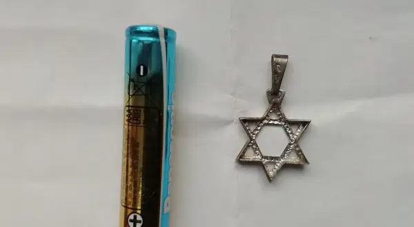 Obok baterii AAA leży srebrny wisiorek w kształcie Gwiazdy Dawida. To symbol, co oznacza przynależność i tożsamość.
