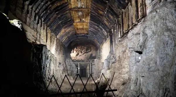 Mroczny tunel kopalni w **Przytkowicach**, z drewnianym stropem i kamiennymi ścianami, prowadzi w głąb ziemi.