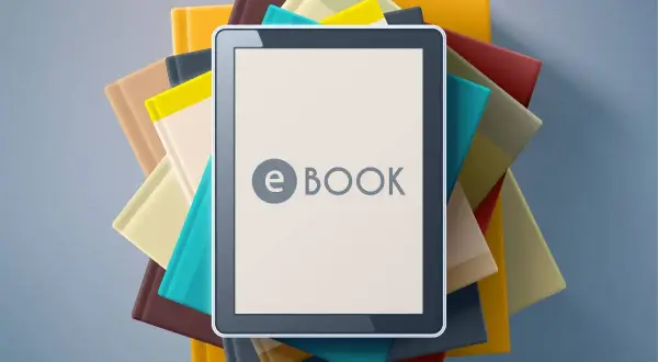 Une tablette affiche "e BOOK" au milieu d'une pile de livres colorés. C'est quoi un ebook ? Une nouvelle façon de lire !