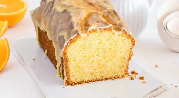 Bizcocho de naranja y chocolate cubierto con glaseado, con rodajas de naranja al lado.