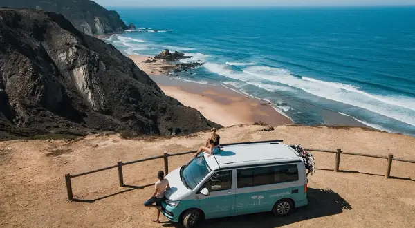 Ein Campervan steht am Rand einer Klippe mit Blick auf den Ozean. Perfekt für einen roadtrip portugal 10 tage.