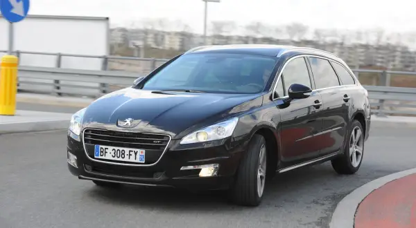 Czarny Peugeot 508 GT na drodze, przygotowany do wymiany żarówki z przodu.