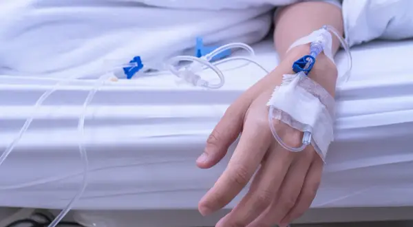 Ręka pacjenta z wenflonem, podłączona do kroplówki. Leczenie hipernatremii.