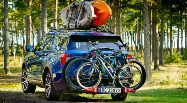 Gotowi na przygodę! Błękitny SUV z rowerami na bagażniku i kajakami na dachu, idealny na pętlę bieszczadzką.