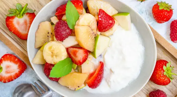 Frischer Obstsalat mit Joghurt, Erdbeeren, Bananen, Äpfeln und Himbeeren. Ein einfaches obstsalat rezept für jeden Tag.