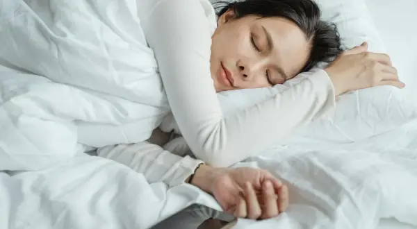 A woman sleeps peacefully, perhaps a natural short sleeper, with her phone nearby.
