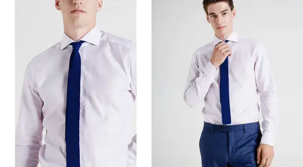 Uomo con camicia per cravatta rosa pallido e cravatta blu a maglia. Pantaloni blu eleganti.