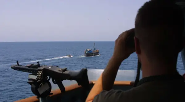 Mann mit Fernglas beobachtet ein Schiff, während ein Maschinengewehr bereitsteht. Möglicherweise ein Einsatz von Smit Salvage.