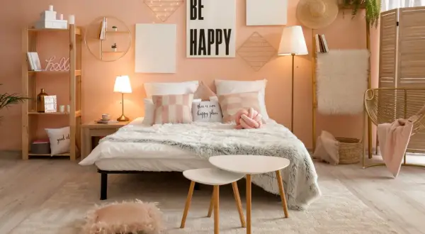 Sypialnia w stylu kawaii: łóżko z puszystymi kocami, poduszki w pastelowych kolorach, dekoracje ścienne z lampkami i napis "BE HAPPY".