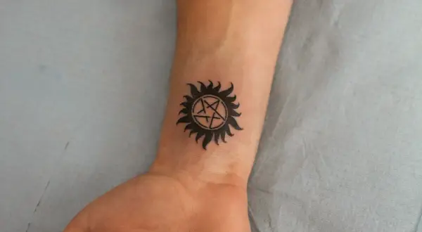 Tatuaże ochronne znaczenie: symbol gwiazdy w okręgu z promieniami na nadgarstku, symbolizujący ochronę przed złem.