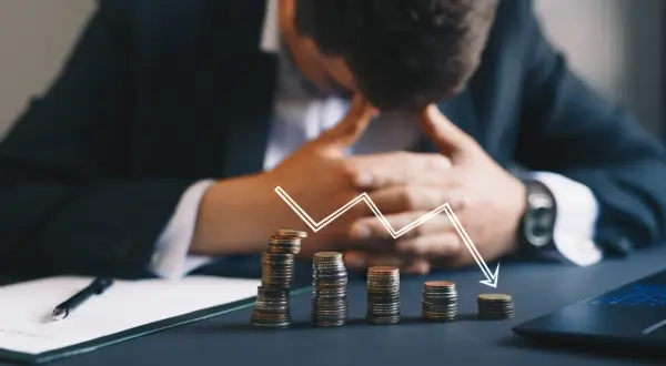 Zastanawiasz się, kto z polskich celebrytów ogłosił upadłość konsumencką w tym miesiącu? Obrazek pokazuje stosy monet i wykres spadkowy, symbolizujące problemy finansowe.