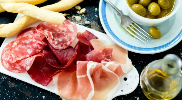 En härlig italiensk tapasbricka med salami, prosciutto, grissini, oliver och olivolja. Perfekt för en mysig kväll.