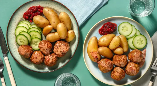 Två tallrikar med köttbullar, potatis, gurka och lingonsylt. Enkla nyttiga recept som dessa är perfekta för en snabb middag.