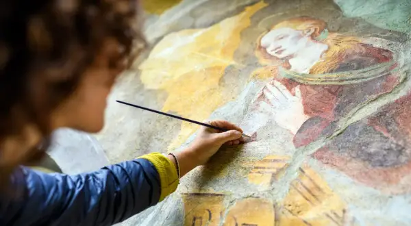 Restauration d'une vieille peinture qui sent mauvais, une main délicate redonne vie à une fresque ancienne.