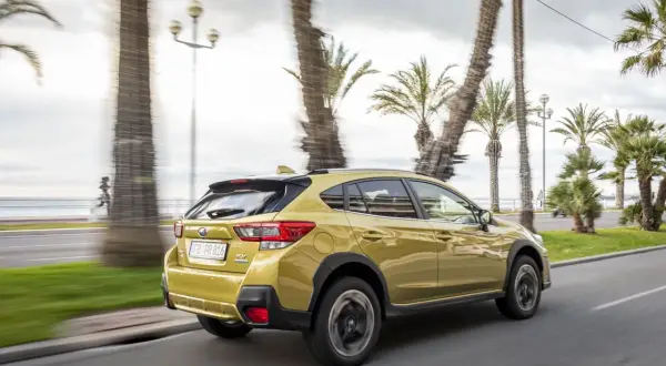 Złoty Subaru XV 2.0 benzyna jedzie wzdłuż nadmorskiej promenady, mijając palmy i biegacza.