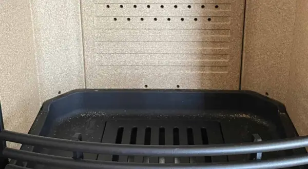 Intérieur d'un poêle, prêt à remplacer la vermiculite par fonte. Grille en fonte et parois texturées.