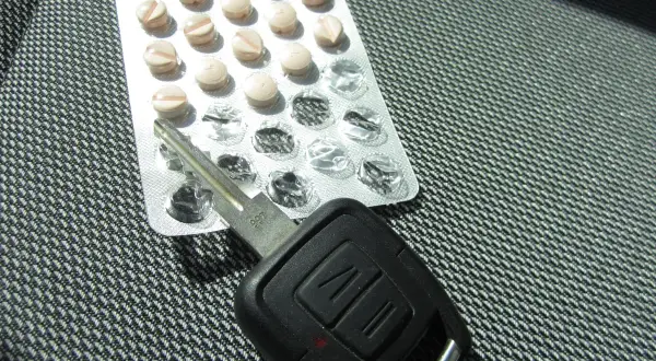 Tabletten und Autoschlüssel liegen nebeneinander. Vorsicht beim tilidin autofahren!