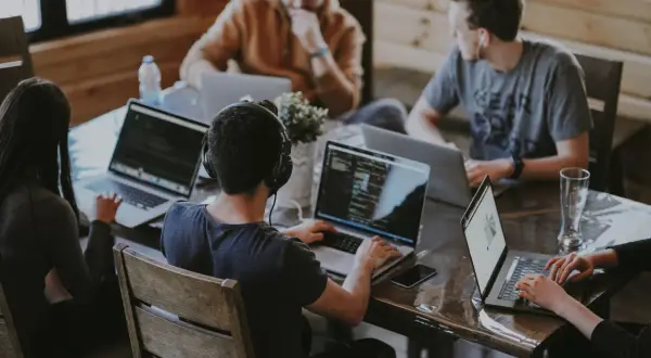 Grupa osób pracuje przy laptopach, dyskutując o regulaminie pracy.