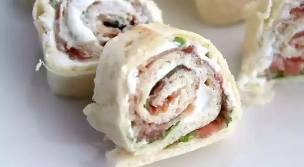 Rouleaux de pain de mie garnis de fromage frais et de jambon, coupés en tronçons pour un apéritif gourmand.