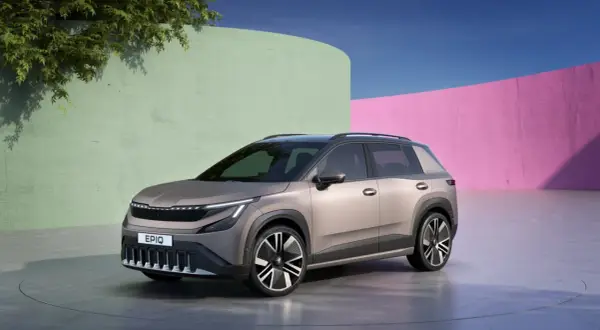 Nowy, elektryczny SUV Škoda Enyaq, z nowoczesnym designem i napisem Enyaq na grillu, prezentuje się na tle kolorowych ścian.