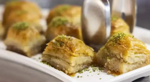 Słodka baklava, co to? Warstwy ciasta filo, orzechów i syropu, posypane pistacjami. Idealna na deser.